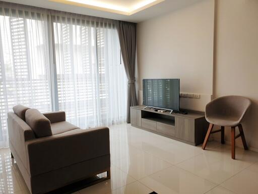 Modern living room with large windows, sofa, TV, and chair