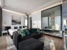 Modern bedroom with a seating area, large bed, and partial glass wall revealing an ensuite bathroom