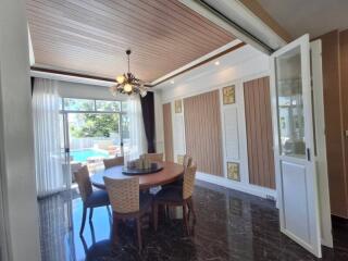 Modern dining room with a round table and chairs, near large windows and a view of a pool.