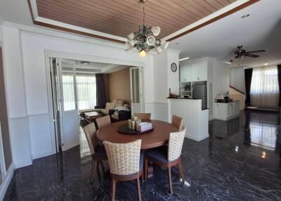 Modern dining room and open living area with wooden ceiling accents and chandelier