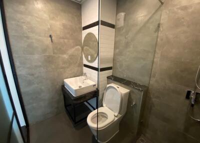 Modern bathroom with glass-enclosed shower, sink, and toilet