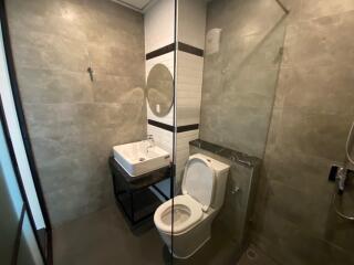 Modern bathroom with glass-enclosed shower, sink, and toilet