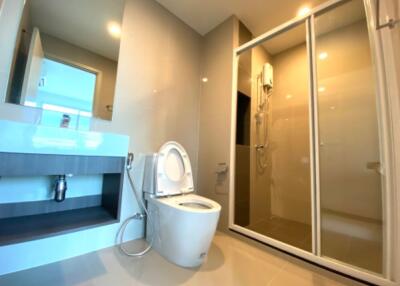 Modern bathroom with a toilet, sink, and shower enclosure