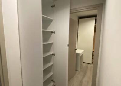 White hallway with built-in shelves and light wood flooring