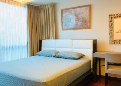 Modern bedroom with hardwood floors, a double bed with blue bedding, a window with curtains, and a desk with a chair