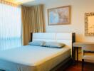 Modern bedroom with hardwood floors, a double bed with blue bedding, a window with curtains, and a desk with a chair