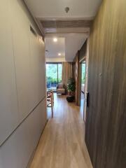 Hallway view leading to a living area with large windows