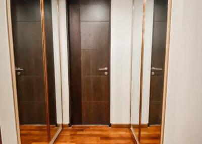 Narrow hallway with wooden doors and mirrored closets