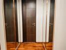 Narrow hallway with wooden doors and mirrored closets