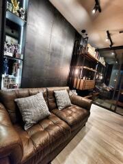 Modern living room with leather sofa, decorative shelves, and ambient lighting