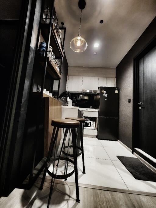 Modern kitchen with stools, black refrigerator, and open shelving