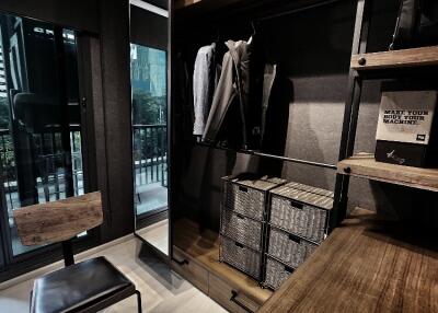 Well-organized walk-in closet with hanging space, storage bins, and seating area