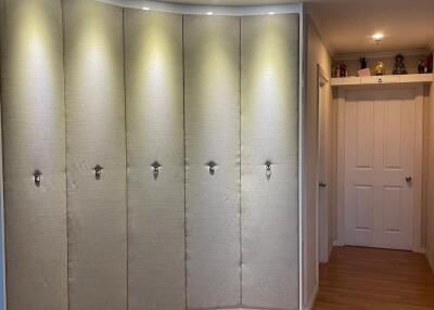 A hallway with a curved, lighted wall and light wood flooring