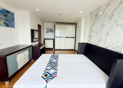 Modern bedroom with a large bed, marble accent wall, wardrobe, and chest of drawers