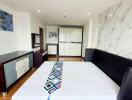 Modern bedroom with a large bed, marble accent wall, wardrobe, and chest of drawers