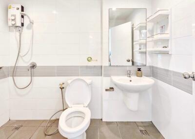 Modern bathroom with white tiles, showerhead, toilet, and sink