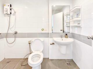 Modern bathroom with white tiles, showerhead, toilet, and sink