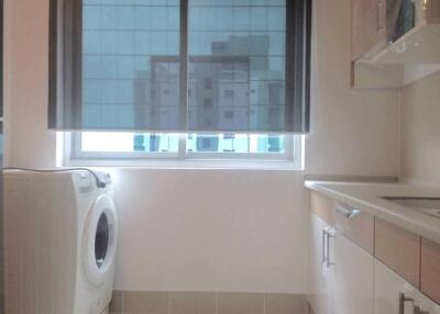 Laundry room with a washing machine and window