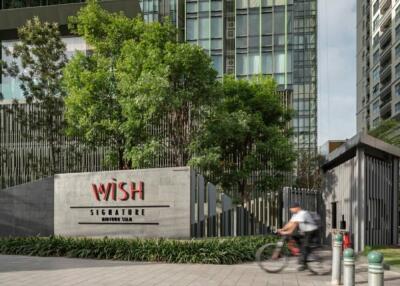 Exterior view of modern high-rise building with greenery and entrance sign