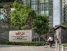 Exterior view of modern high-rise building with greenery and entrance sign