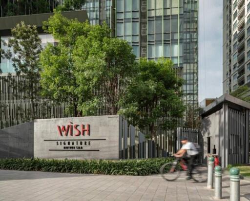 Exterior view of modern high-rise building with greenery and entrance sign