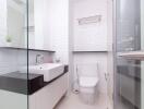 Modern bathroom with white tiles, sink, and toilet