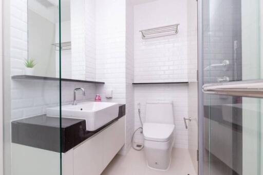 Modern bathroom with white tiles, sink, and toilet