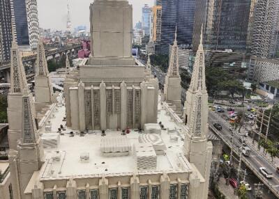 Aerial view of a large, modern building with tall spires, surrounded by a cityscape.