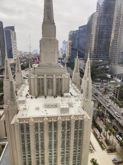 Aerial view of a large, modern building with tall spires, surrounded by a cityscape.