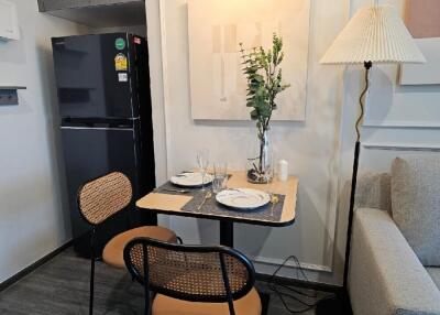 Cozy dining area with a small table set for two, black refrigerator, and a decorative wall art