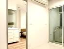 Bedroom with white walls, wooden flooring, air conditioner, and a glass door leading to another room