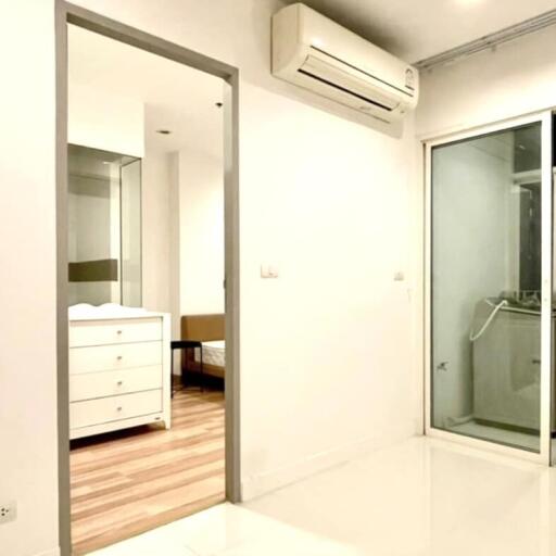 Bedroom with white walls, wooden flooring, air conditioner, and a glass door leading to another room