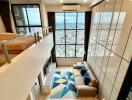 Modern loft-style living room with a mezzanine bedroom, large floor-to-ceiling windows, and a stunning city view