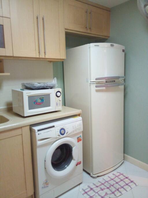 Small kitchen with refrigerator, washing machine, microwave, and wooden cabinets