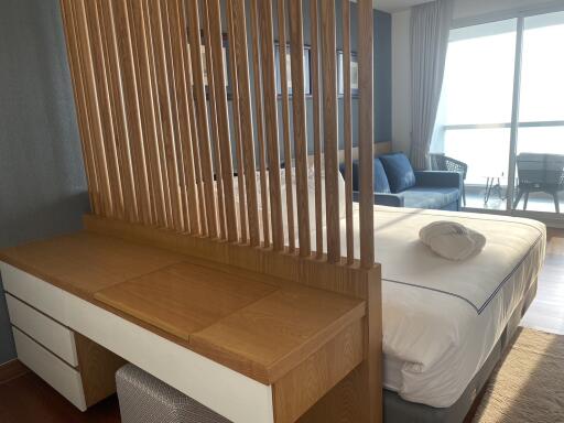 Well-lit modern bedroom with a wooden room divider and a seating area