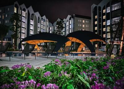 Night view of modern apartment complex with pool and lounge area