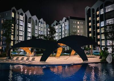 Modern apartment complex at night with pool and lounge area