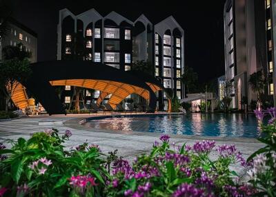 Night view of an apartment complex with a swimming pool and garden