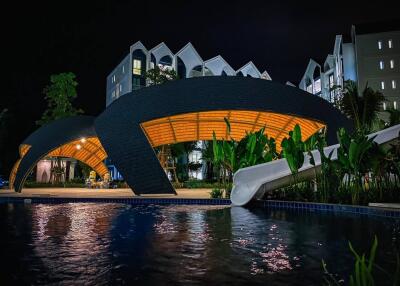 Residential building with a lit arch structure and swimming pool at night