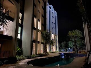 Outdoor view of an apartment building with a pool at night