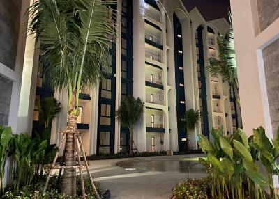 Night view of a multi-story residential building with balconies and palm trees