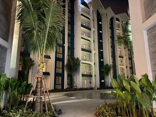 Night view of a multi-story residential building with balconies and palm trees