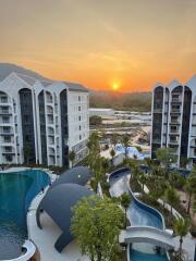 View of modern residential buildings and landscaped pool area at sunset