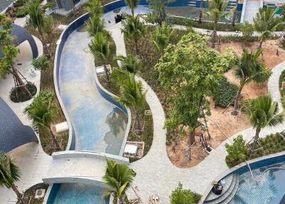 Aerial view of modern apartment building with landscaped garden and multiple pools