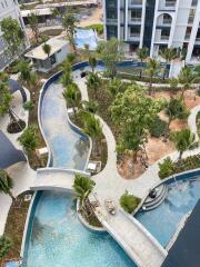 Aerial view of modern apartment building with landscaped garden and multiple pools