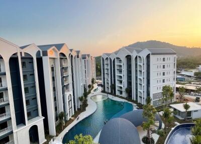 Aerial view of a modern apartment complex with a pool and sunset