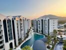 Aerial view of a modern apartment complex with a pool and sunset