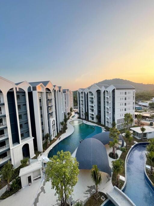 Aerial view of a modern apartment complex with a pool and sunset