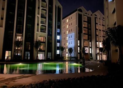 Outdoor view of residential buildings at night with illuminated swimming pool