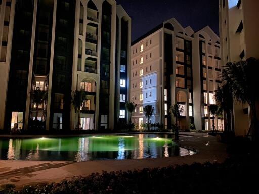 Outdoor view of residential buildings at night with illuminated swimming pool